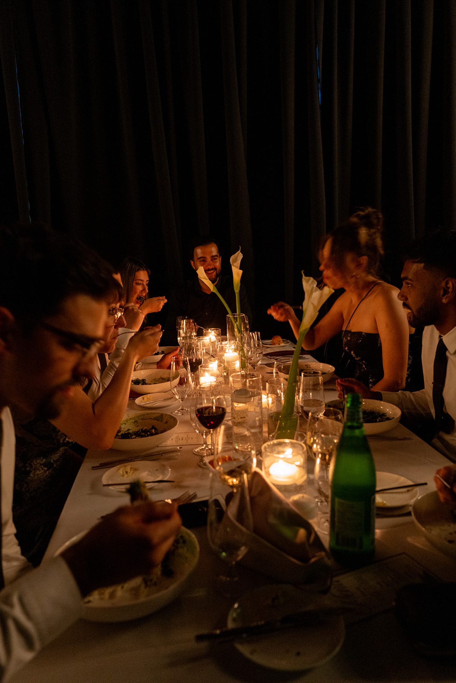Guests sharing a candlelit dinner around a long table
